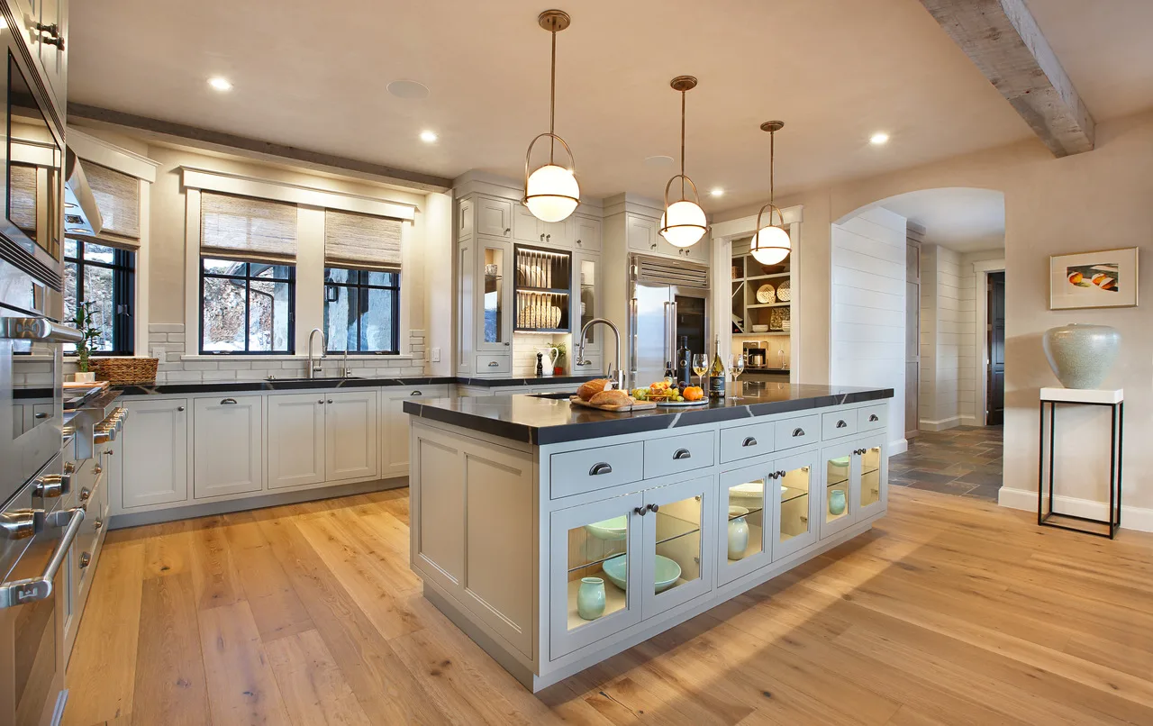 White kitchen with a large island, under-cabinet lighting and wide-plank wood floors