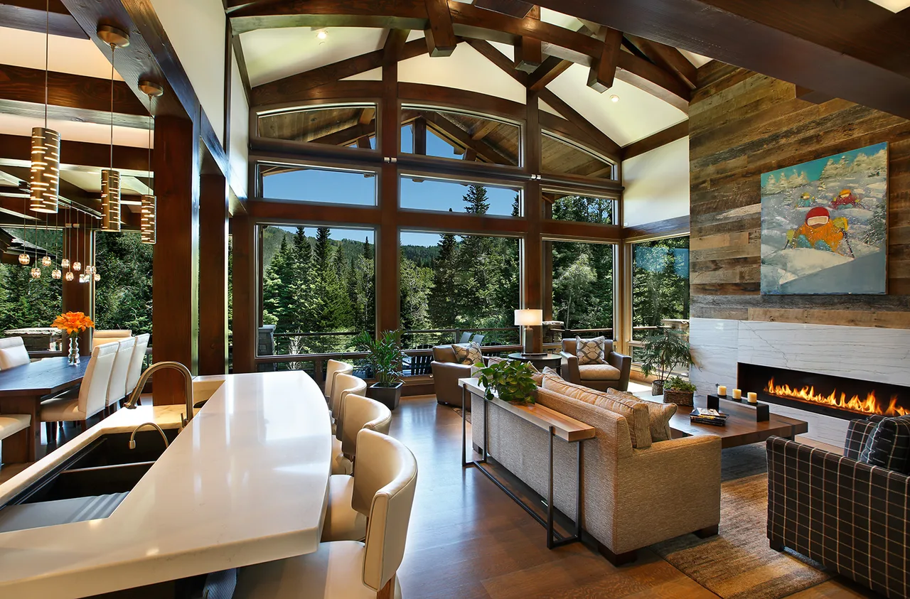 Kitchen with a white waterfall-edge island, cluster pendant lights and a vaulted timber ceiling with a glass wall