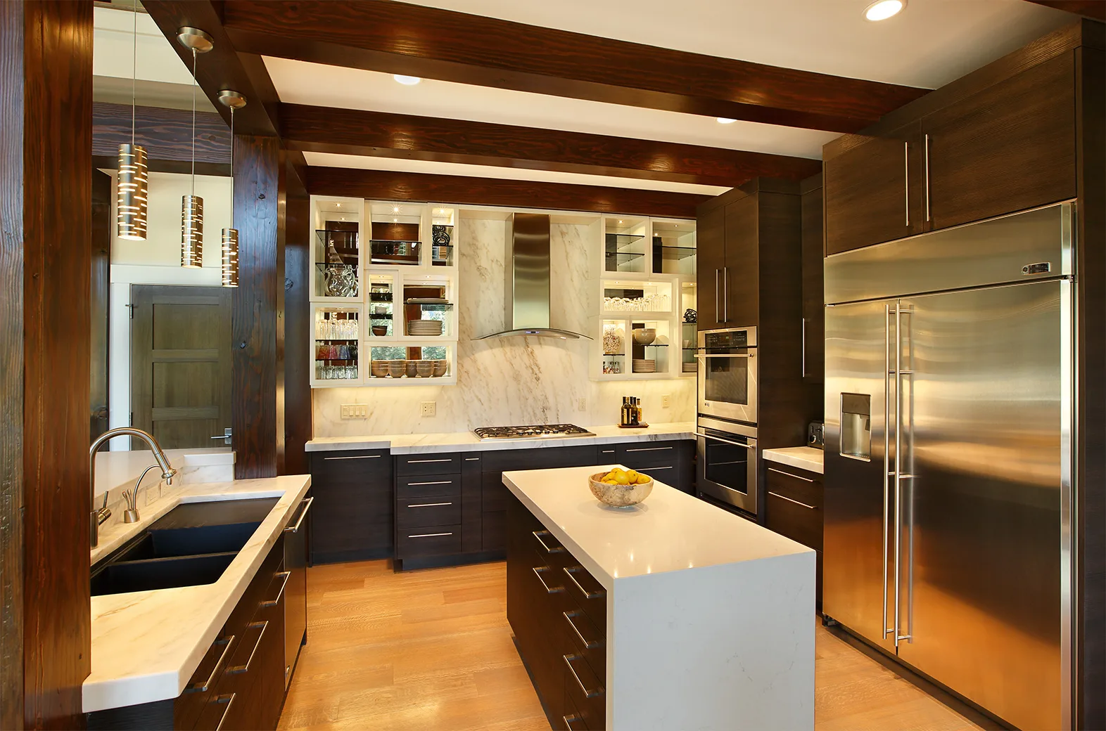 Kitchen with dark cabinetry, a marble backsplash and wood floors