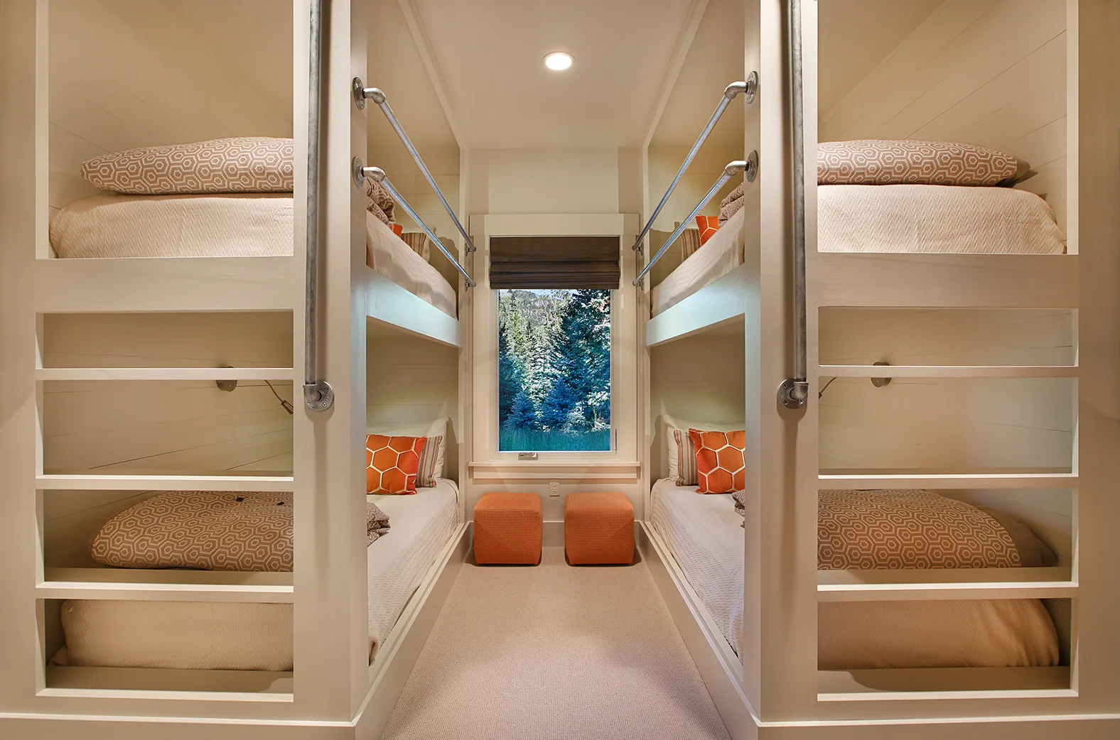 Built-in bunk beds with a ladder and orange throw pillows beside a window
