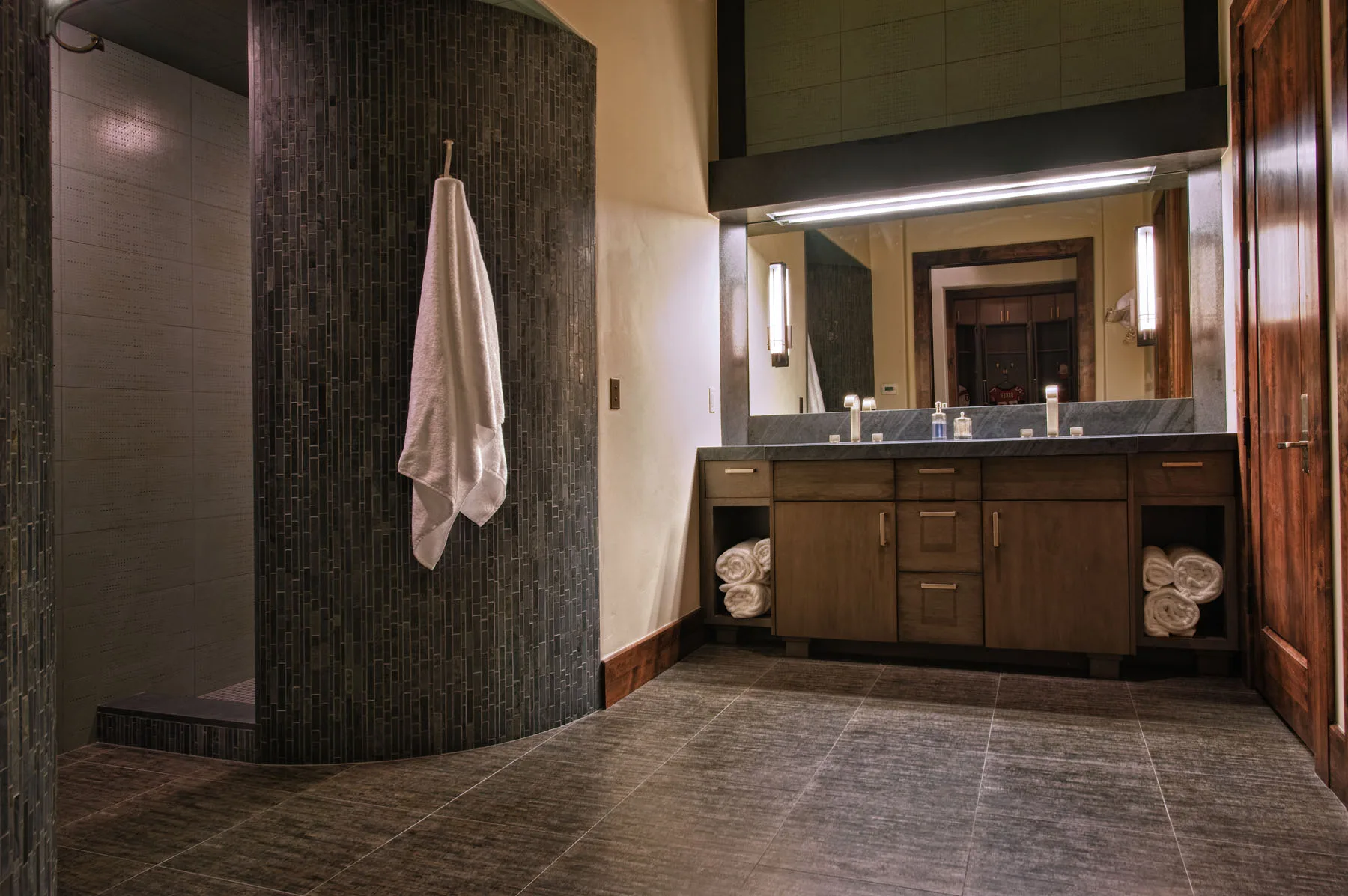 Bathroom with a stone tile shower wall and a folded towel on a hook
