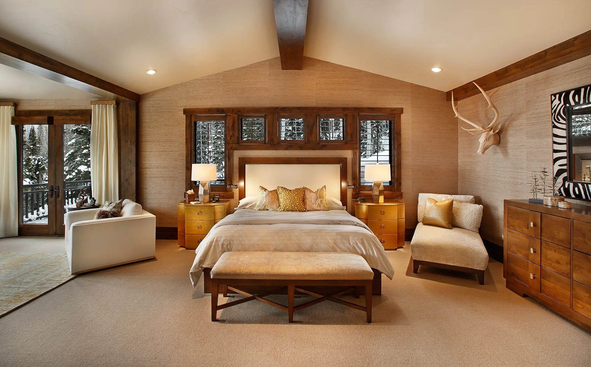Bedroom with a wood bed, armchair and deer skull art above the headboard