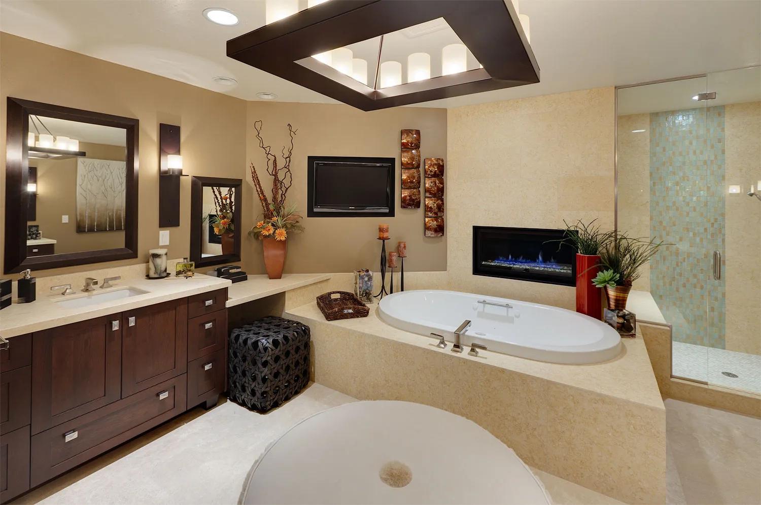 Bathroom with a soaking tub beneath framed art, a fireplace and a mounted TV nearby