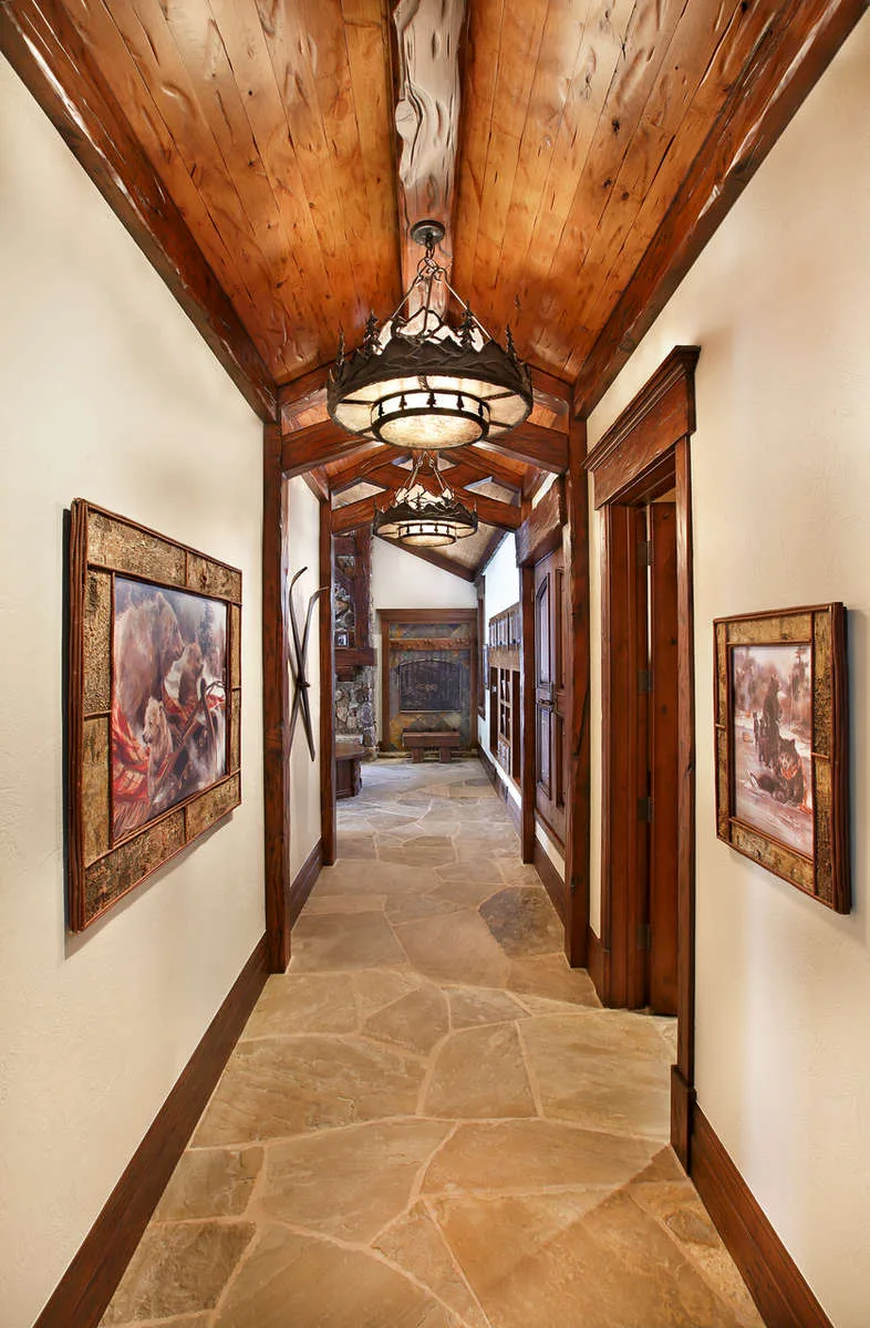 Hallway with a wood beam ceiling, pendant light fixtures and framed art