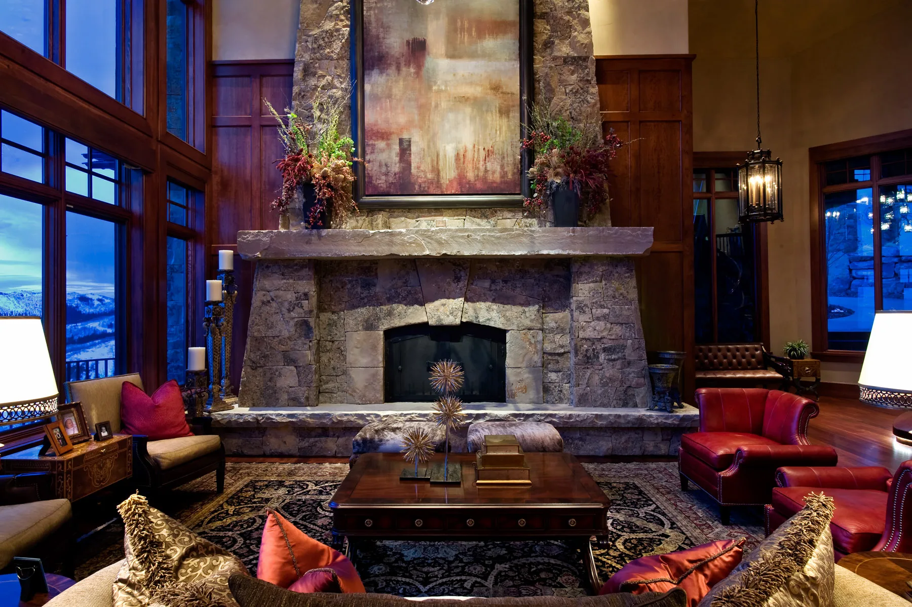 Living room with a stone fireplace, leather chairs and red accent pillows