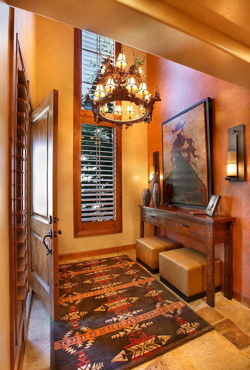 Hallway corner with a chandelier, framed art and shuttered windows