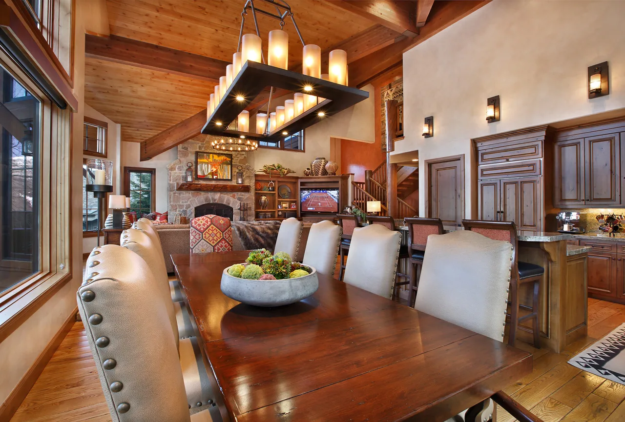 Dining room with a wood table, white upholstered chairs and a cluster pendant light fixture