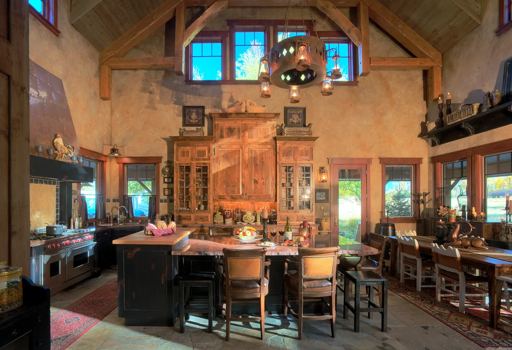 Dining area with a wood table, leather chairs, windows and a pendant chandelier