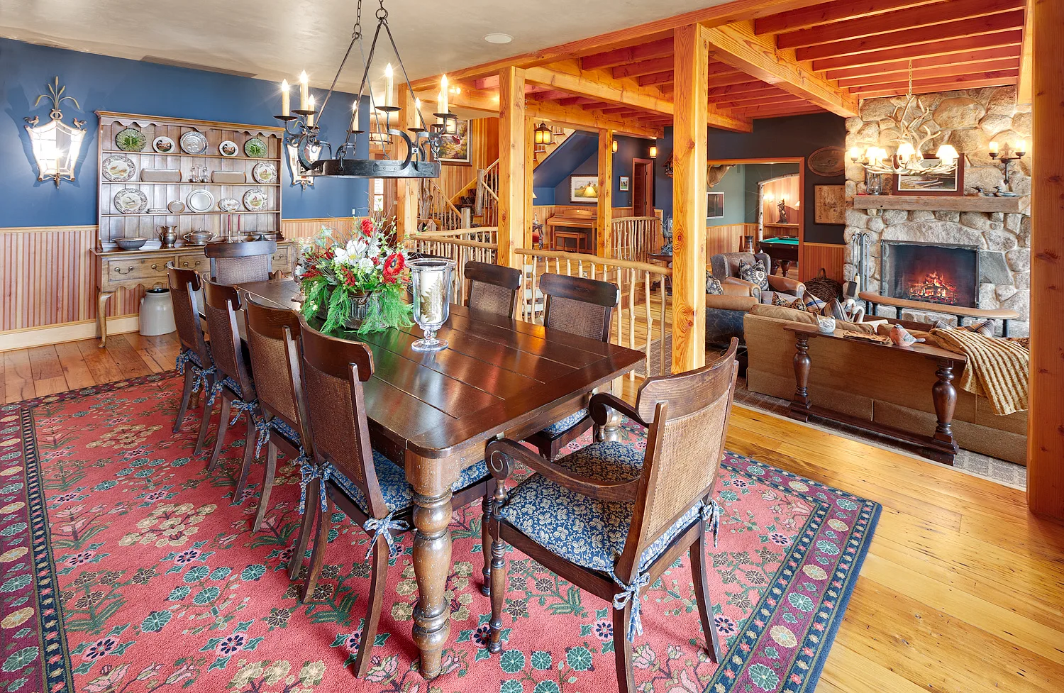 Open dining and living area with timber framing, a fireplace and a rustic chandelier