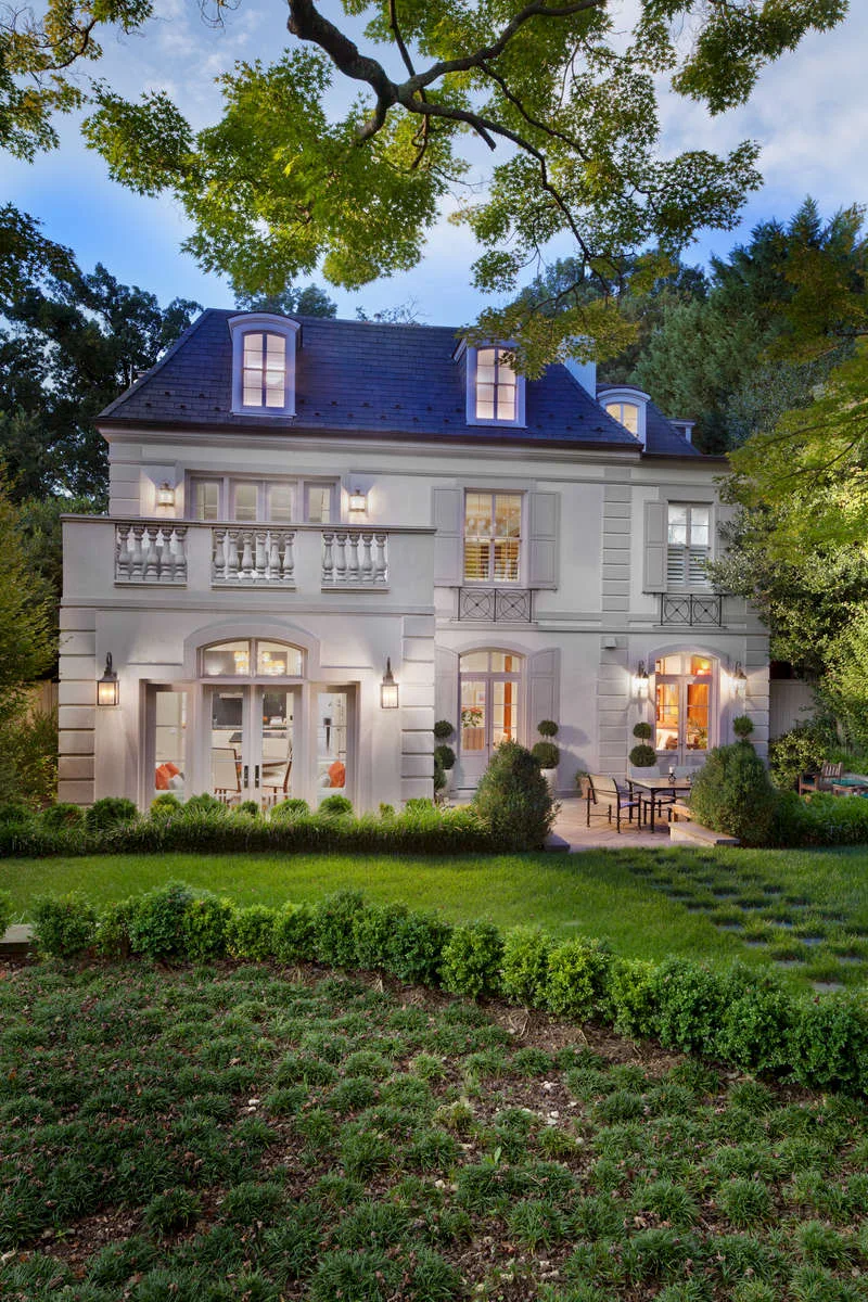 Dusk exterior of the back of a city home with dormer windows and a balcony