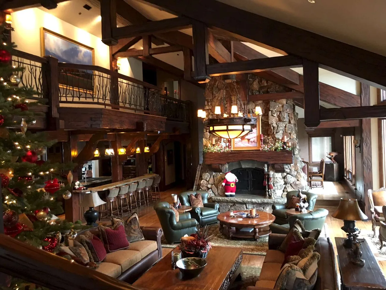 Loft living room decorated for Christmas, with a stone fireplace and wood railings on the level above
